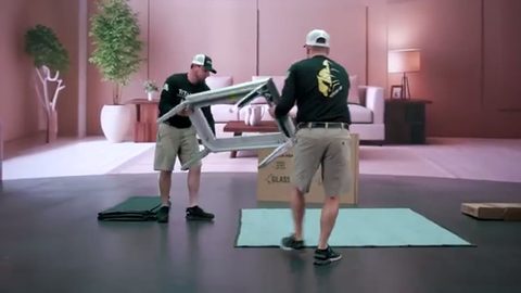 two movers lifting a glass tabletop off its metal base